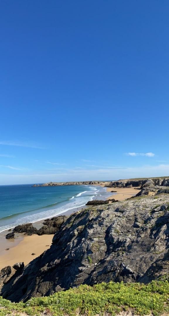 Paesaggio costiero con terreno roccioso e una spiaggia.