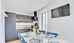 A modern kitchen with grey cabinets, a white dining table set with plates, glasses, and a vase of flowers.