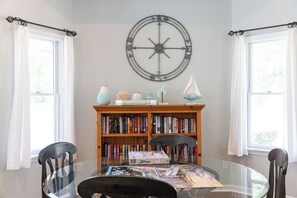 A room with a round wall clock, a bookshelf, a glass table, and two chairs. - Coast to Coast:Dog Friendly, Private Pool, Hot Tub, Community Amenities (Corolla)