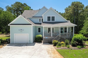 A two-story house with a covered porch, a garage, and a well-maintained lawn.