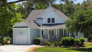 A two-story house with a covered porch, a garage, and a well-maintained lawn. - Coast to Coast:Dog Friendly, Private Pool, Hot Tub, Community Amenities (Corolla)