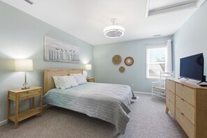 A bedroom with a bed, bedside tables, a dresser, a ceiling fan, a painting, and a window with blinds. - Coast to Coast:Dog Friendly, Private Pool, Hot Tub, Community Amenities (Corolla)