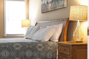 A neatly made bed with patterned bedding, a headboard, two bedside lamps, a nightstand, and a drawer. - Coast to Coast:Dog Friendly, Private Pool, Hot Tub, Community Amenities (Corolla)