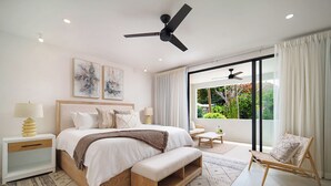 A modern bedroom with a large bed, bedside tables, a ceiling fan, and a view of greenery through a sliding glass door. - NEW villa with plunge pool, 3 mins to beach - Sorrento 10 (Lower Carlton)