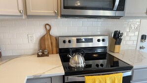 A kitchen with a stainless steel stove, a microwave above, and a yellow towel hanging on the oven door. - Chic Spacious Downtown Home - 5 Mins To Frederick Health Hospital & Fort Detrick (Frederick)