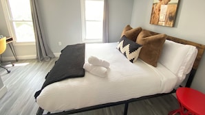 A neatly made bed with white and brown pillows, a dark throw blanket, and a white towel folded on the bed. - Chic Spacious Downtown Home - 5 Mins To Frederick Health Hospital & Fort Detrick (Frederick)