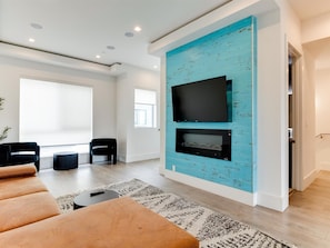 A modern living room with a large flat-screen TV mounted on a blue-painted wall, a sofa, a coffee table, and a patterned rug.