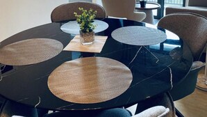 Un'elegante zona pranzo con un tavolo in marmo nero, quattro sedie e un piccolo vaso con una pianta.