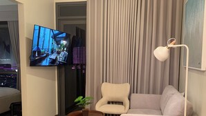 Un soggiorno moderno con una TV a schermo piatto, un divano, una poltrona, un tavolino da caffè e una lampada da terra.