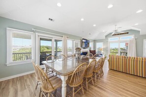 Un comedor con una mesa de vidrio, sillas de madera y vistas al exterior.