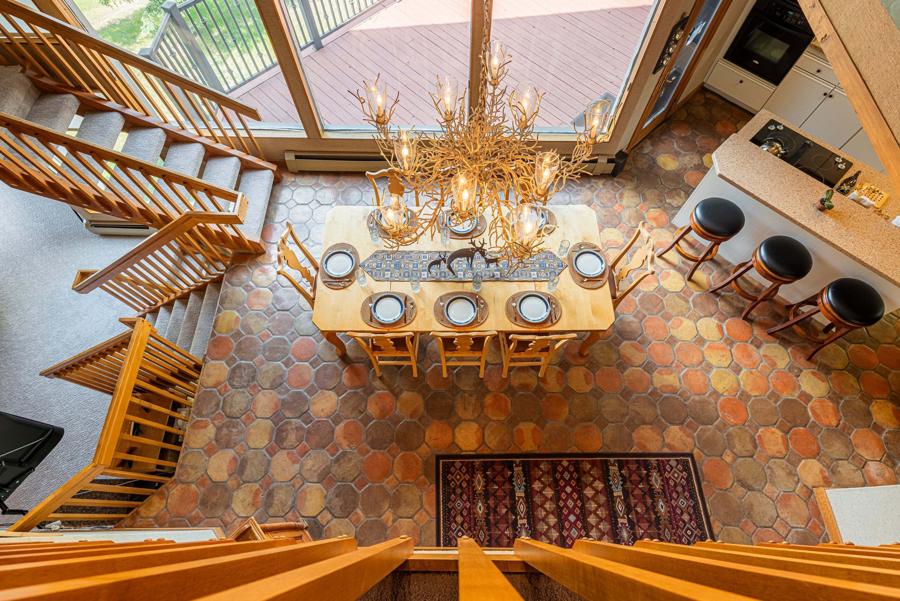 Un espace repas avec une table dressée pour quatre personnes, un lustre et un escalier menant à l’étage supérieur.