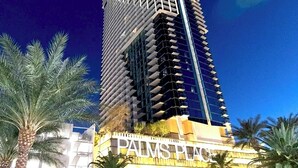 Ein hohes, modernes Gebäude mit einem markanten 'PALMS PLACE'-Schild am Fuße.