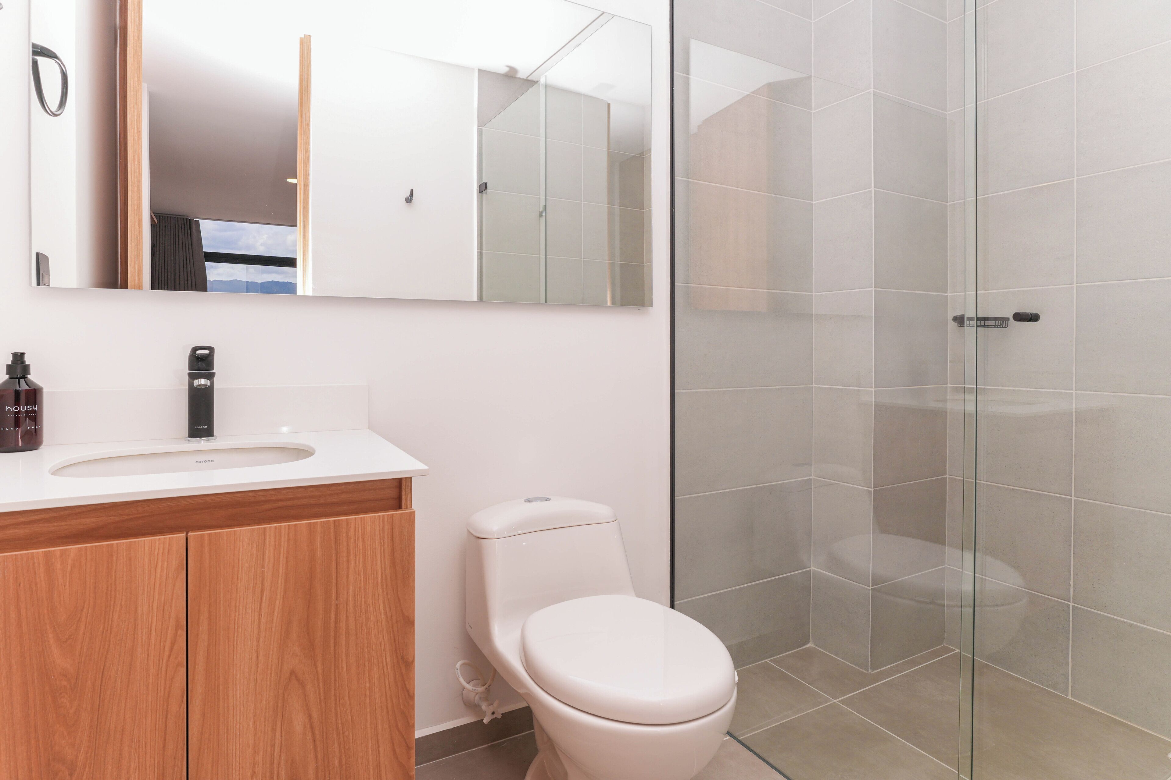 A modern bathroom with a white sink, a toilet, and a glass shower enclosure.
