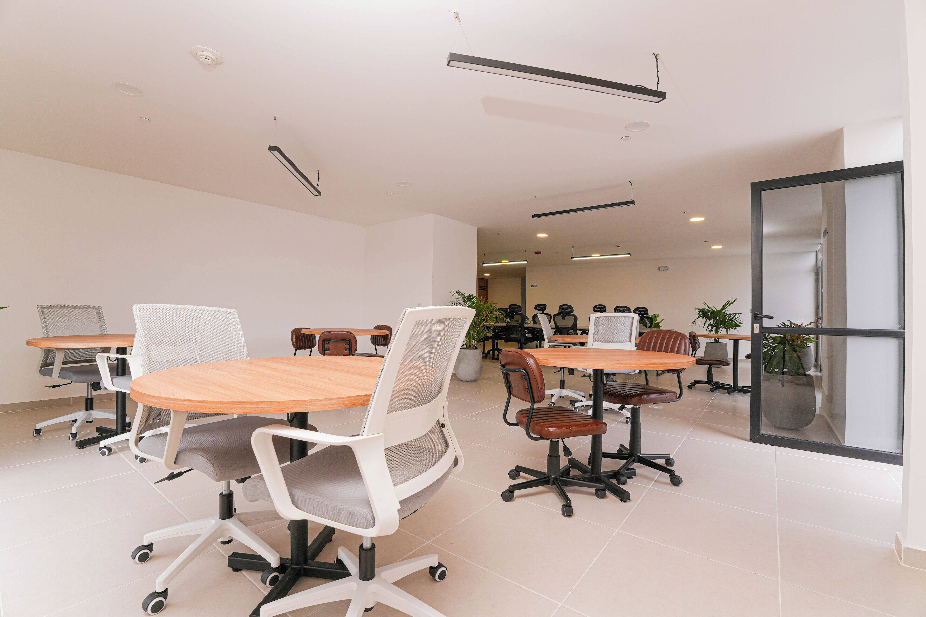 Een moderne vergaderruimte met ronde tafels en witte stoelen, voorzien van individuele monitoren.