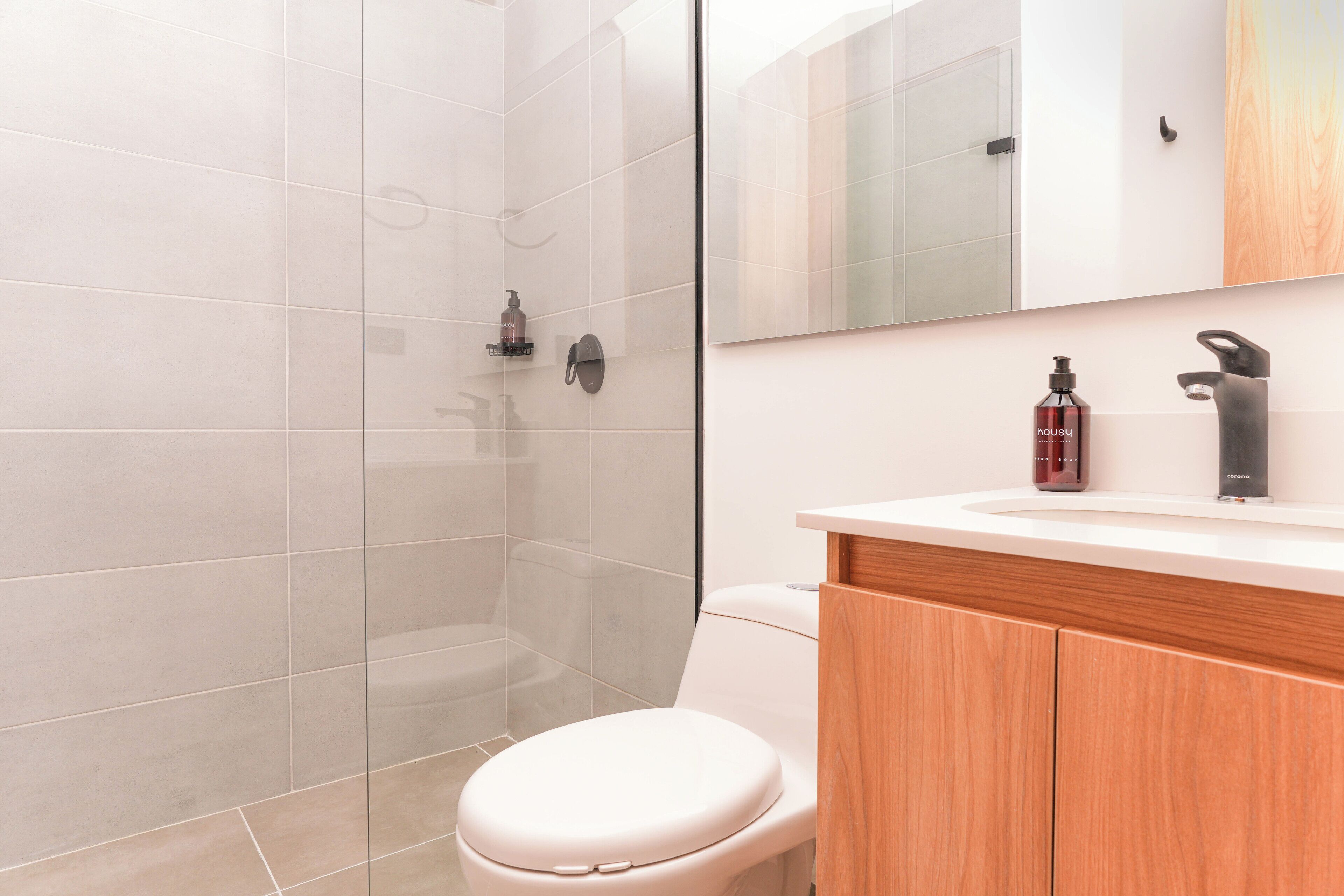 Un bagno moderno con box doccia in vetro, un water e un mobile lavabo con specchio e articoli da toilette.