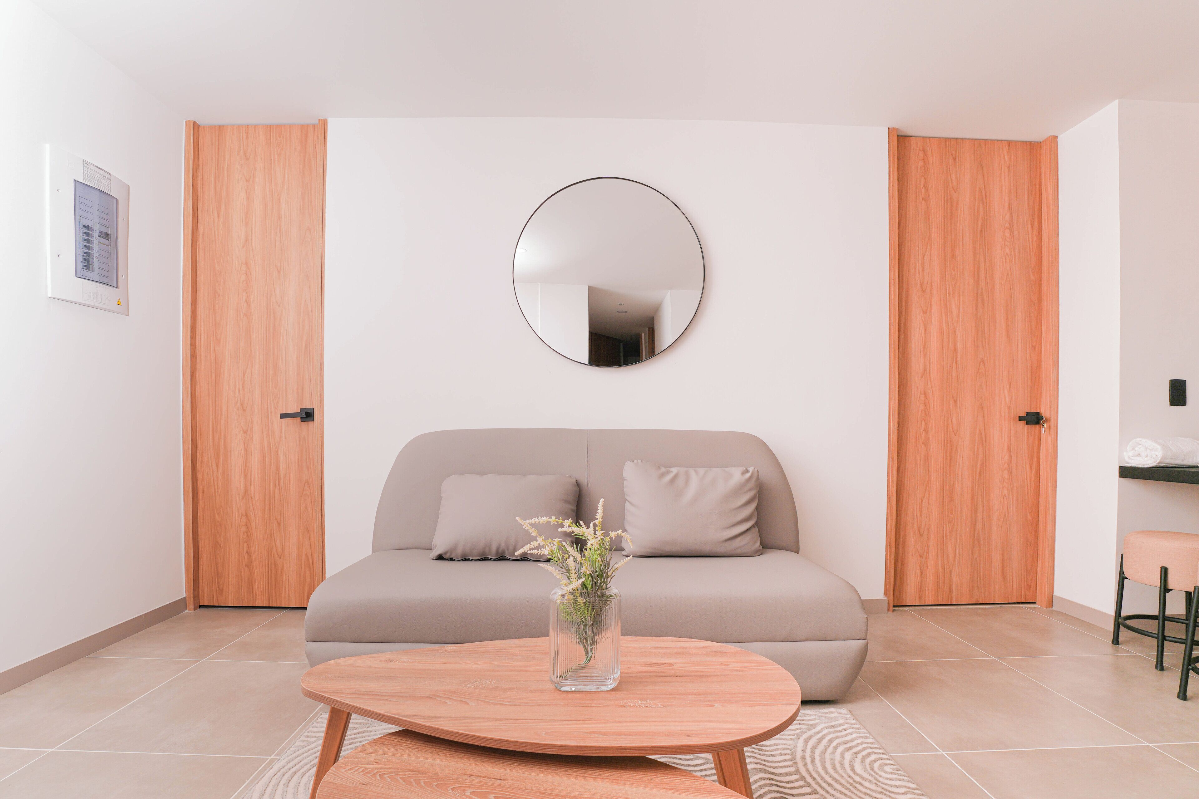 A modern living room with a sofa, a round mirror, and a coffee table.