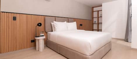 A modern bedroom with a large bed, wooden paneling on the walls, a small bedside table, and a built-in shelf unit.