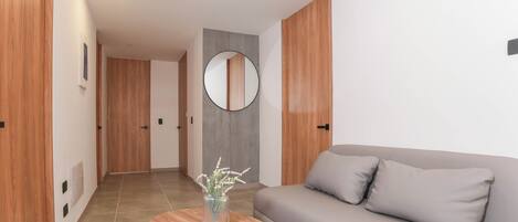 Una sala moderna con un sofá, un espejo redondo y una mesa de centro de madera.