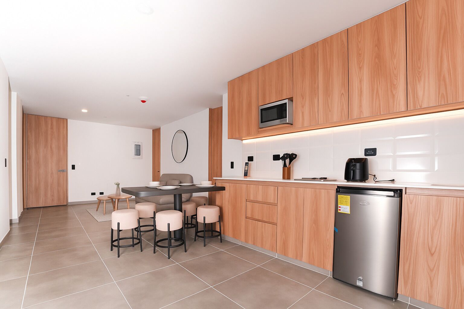 A modern kitchen with wooden cabinets, a stainless steel refrigerator, and a microwave.