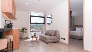 Een modern appartement met een keuken, een zithoek met een bank en een eethoek met krukken.