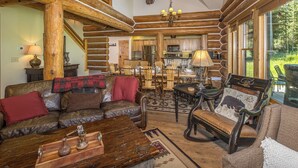 Een rustiek houten interieur met een eethoek, een open haard en een gezellige woonkamer met lederen meubels.