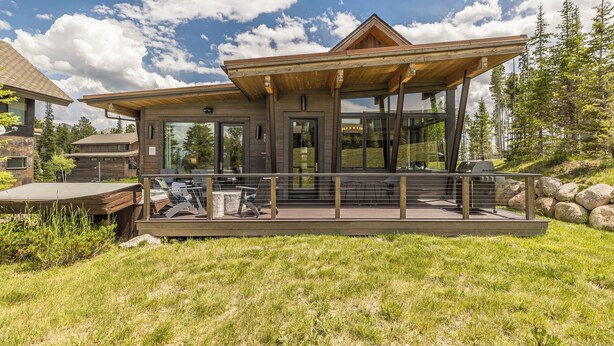 A modern house with a covered patio, large windows, and a stone exterior.
