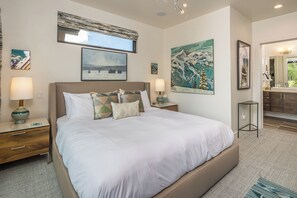 A modern bedroom with a large bed, two bedside tables, a nightstand, and a mirror. - Luxury Moonlight Basin Cabin with Ski-In/Ski-Out Access, Hot Tub & Mountain Views (Big Sky)