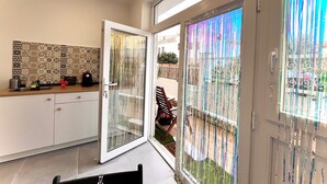 Una cocina moderna con un salpicadero estampado, una puerta corredera de cristal que da a un balcón y una zona de comedor con un banco.