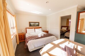 Ein Hotelzimmer mit Bett, Nachttischen, einem Spiegel und einem mit Vorhängen drapierten Fenster.