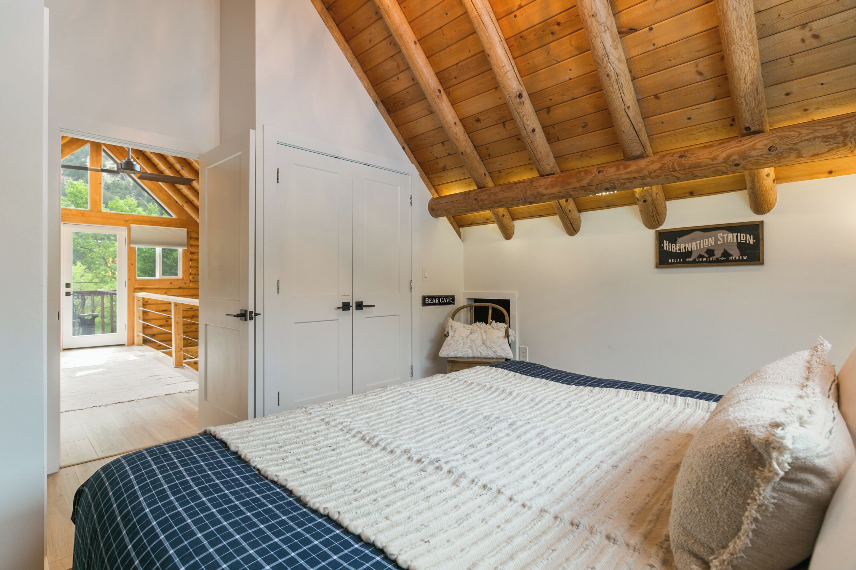 Ein Schlafzimmer mit einem großen Bett, Holzbalkendecke, einem weißen Kleiderschrank und einem Schild mit der Aufschrift 'Hibernation Station'.