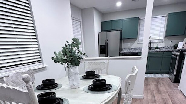 A dining area with a white table set for four, surrounded by white chairs. - Retreat at Stone Mountain – Cozy 3BR Near Trails, MARTA & Downtown (Stone Mountain)