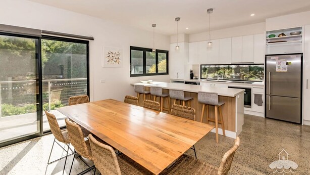 A modern kitchen with a wooden dining table, bar stools, and a stainless steel refrigerator. - 1 Anderson Ave Sandy Point (Sandy Point)