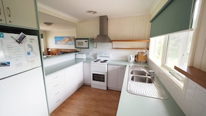 A compact kitchen with a stove, sink, and cabinets. - 27 Beach Parade Sandy Point (Sandy Point)