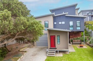 A modern two-story house with a red door, a small front porch, and a well-maintained garden. - 37 Oceanview Pde Sandy Point (Sandy Point)