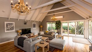 A spacious living room with a high ceiling, a chandelier, a television, a sofa, and a coffee table.