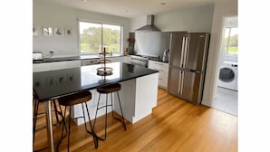 Una cocina moderna con una isla central, electrodomésticos de acero inoxidable y vistas al exterior.