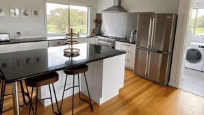 Een moderne keuken met een centraal eiland, roestvrijstalen apparatuur en uitzicht op de omgeving.