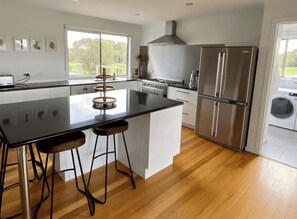 Una cocina moderna con una isla central, electrodomésticos de acero inoxidable y vistas al exterior.