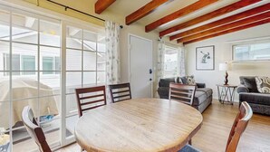 A spacious living area with a round wooden table, two sofas, and a large window with curtains.