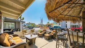 An outdoor patio area with wicker furniture and a thatched roof.
