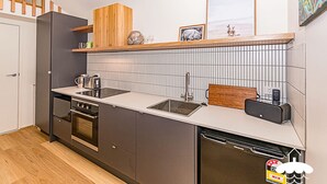 A compact kitchen with a built-in oven, a dishwasher, and a countertop with a sink and a toaster.