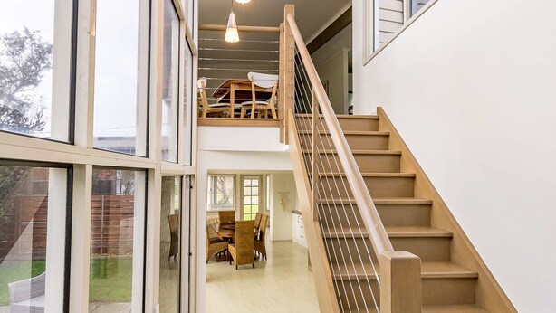 Un intérieur moderne avec un escalier, de grandes fenêtres et un coin repas.