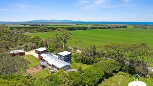 Une maison moderne dotée d’un grand jardin, entourée d’une végétation luxuriante et offrant une vue sur l’océan.
