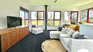 Un salon moderne doté d’un grand téléviseur, d’un meuble en bois, d’une cheminée et d’un ensemble de canapés.