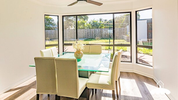 A dining area with a glass table and chairs, large windows, and a view of the backyard. - Fishermans Stay at Port Franklin (Port Franklin)