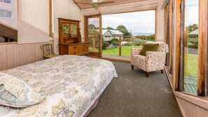 A bedroom with a bed, a chair, a dresser, and a large window.