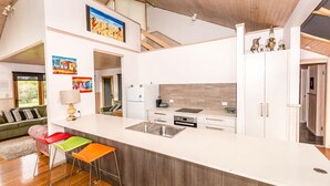 A modern kitchen with a large island, stainless steel appliances, and a view to the living area.