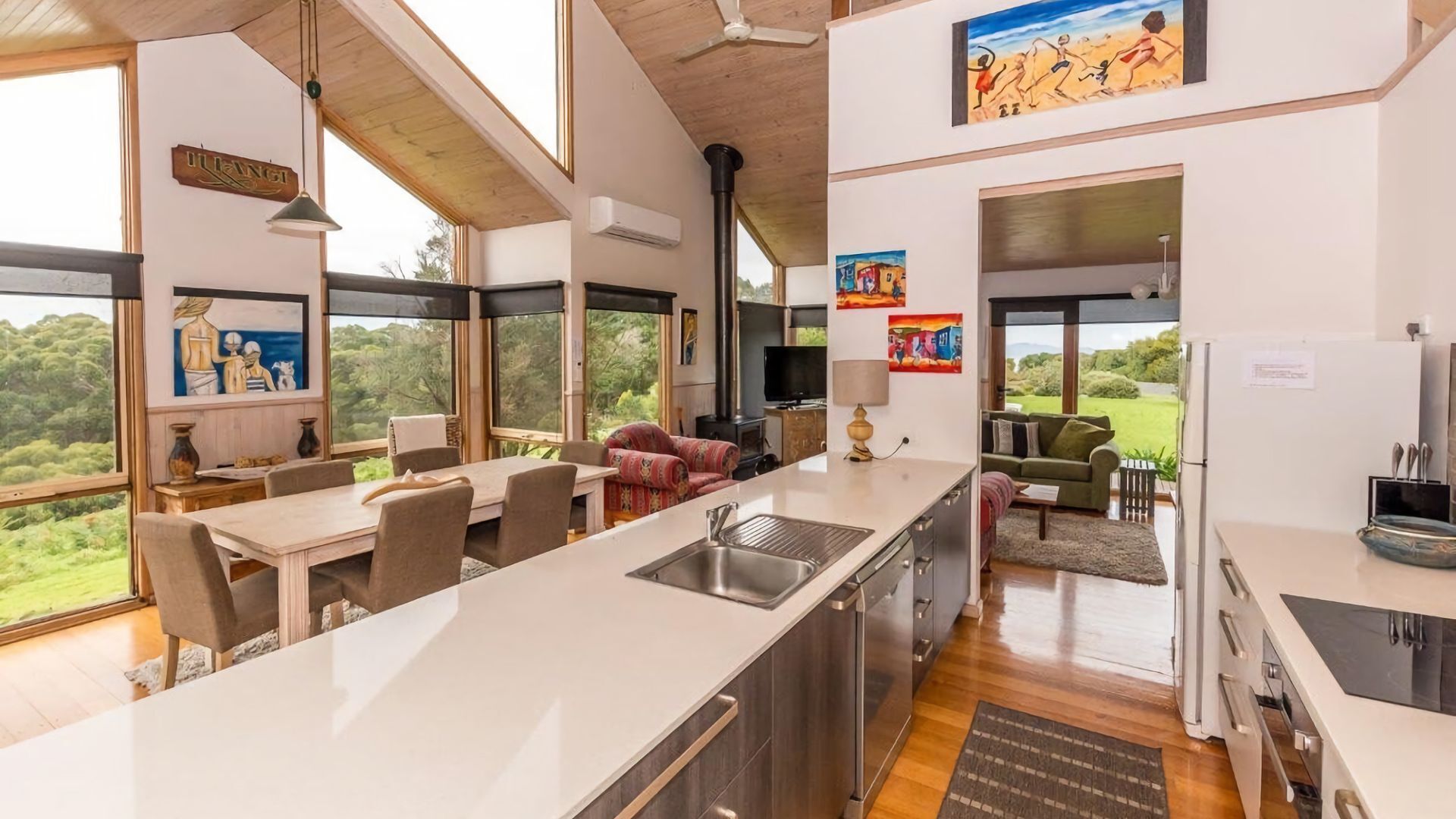 A modern kitchen with a large island, dining area, and a cozy seating space with a view of the outdoors.