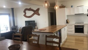 Une cuisine moderne avec des meubles blancs, un îlot central en bois et des luminaires suspendus.