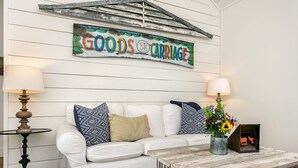 A white wooden wall with a 'GOODS & CARRIAGE' sign. - Smith House | 2/1, Kitchenette, Gas Firepit (Fredericksburg)